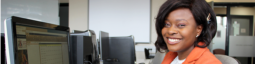 Lady smiles at camera while she works on a computer